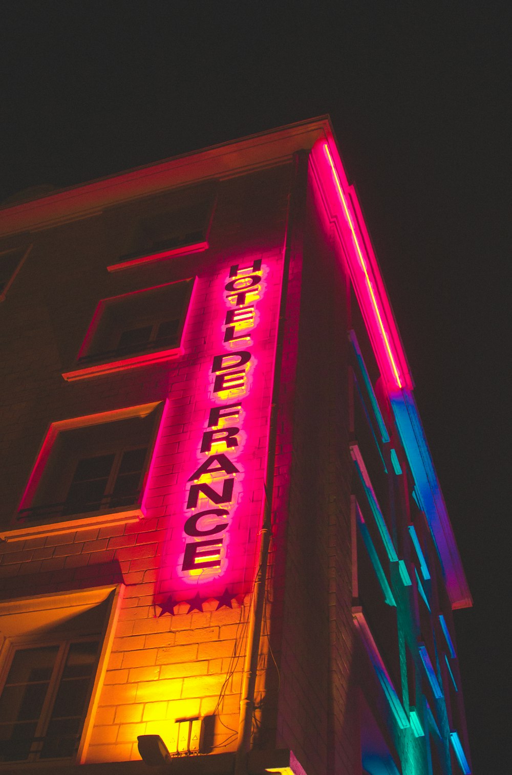 a tall building with a neon sign on it's side