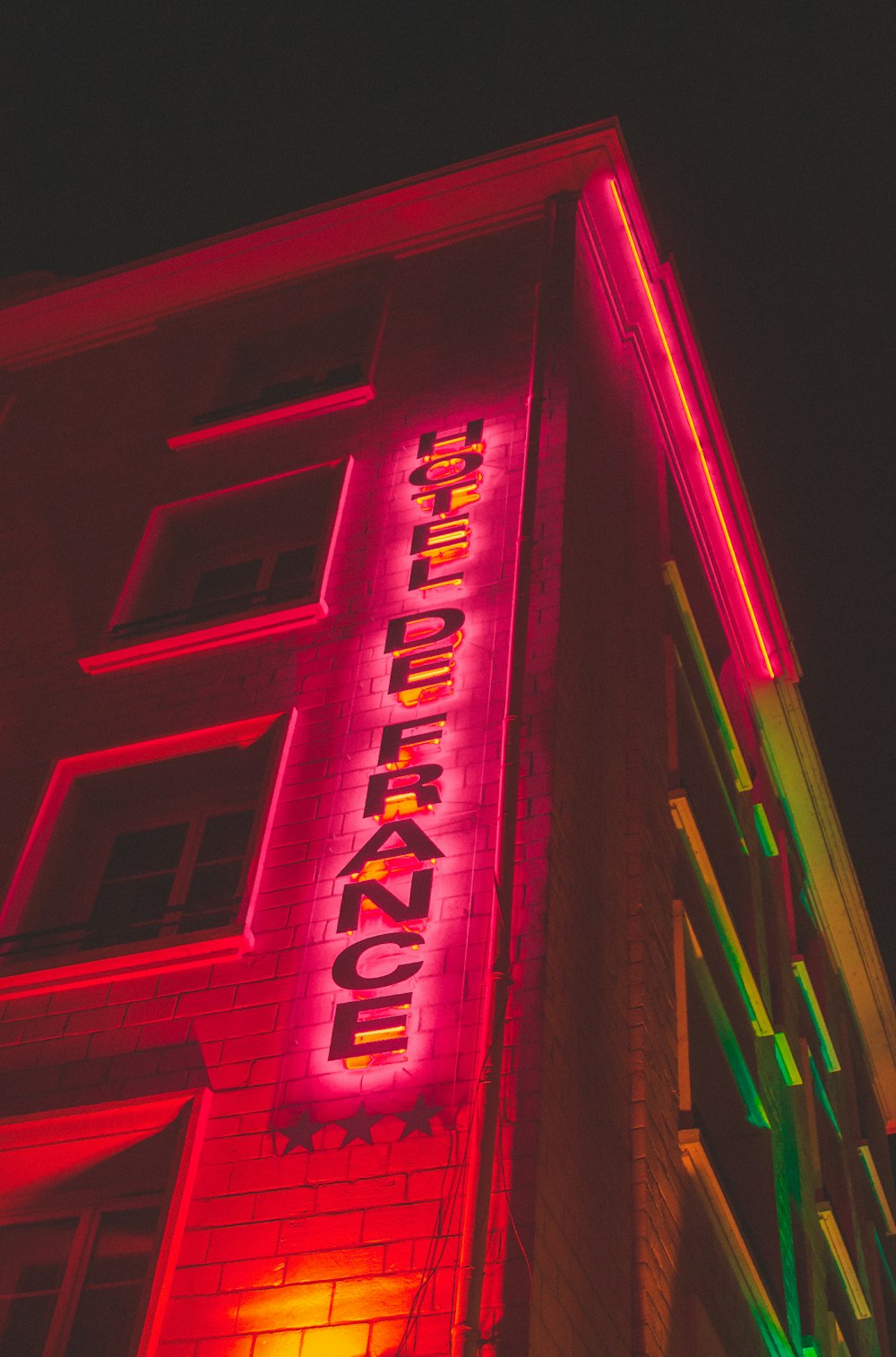 a tall building with a neon sign on it's side