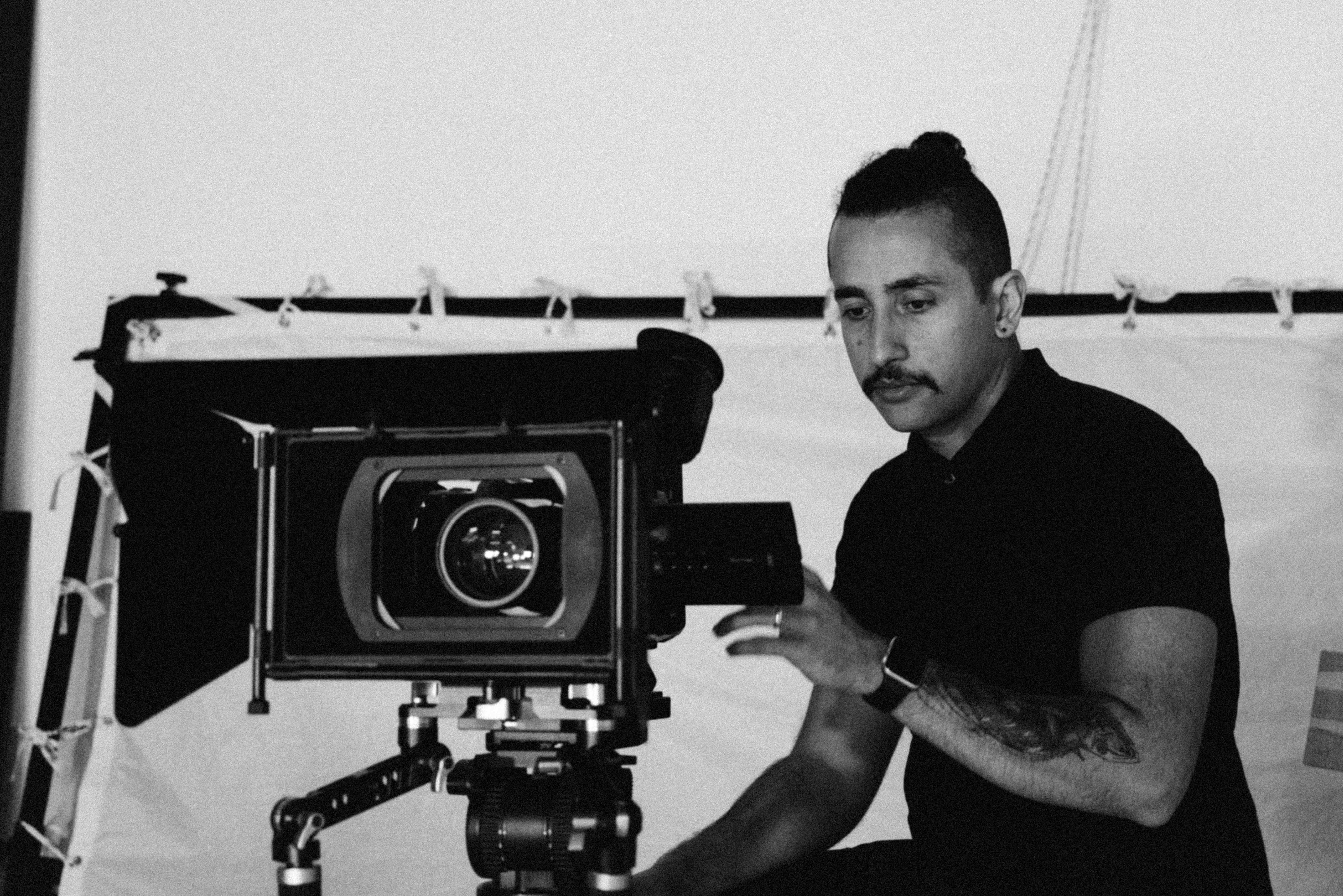 a black and white photo of a man sitting in front of a camera