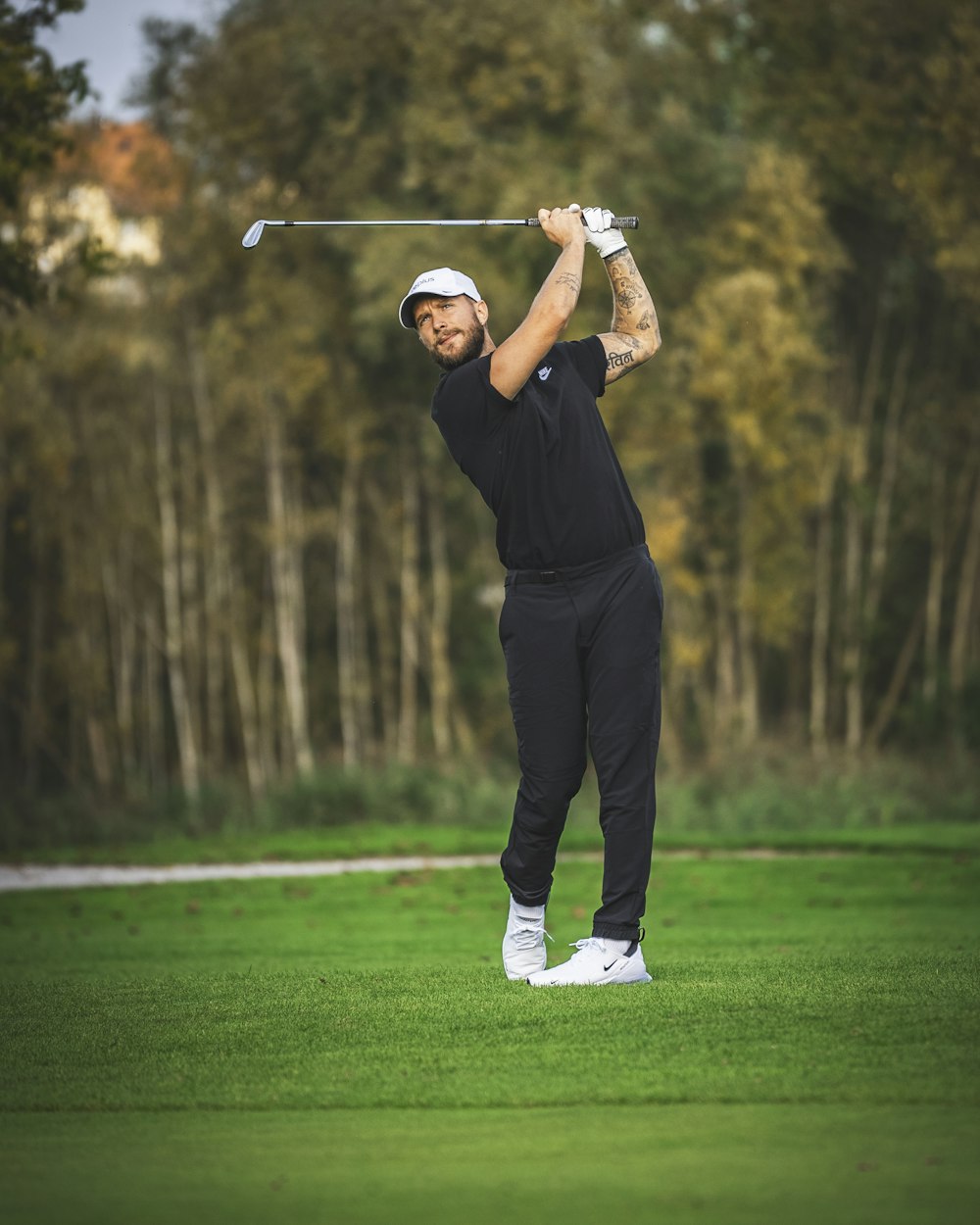 a man swinging a golf club on top of a green field