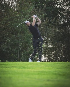 a man swinging a golf club on top of a lush green field