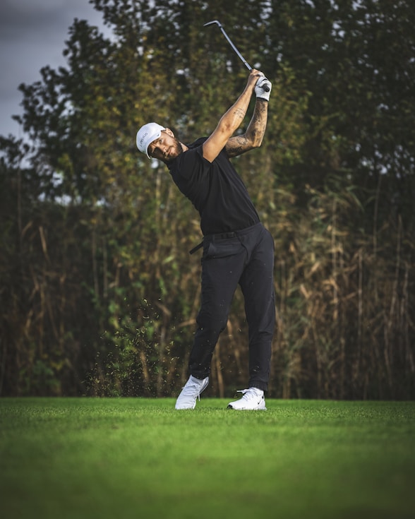 a man swinging a golf club on top of a green field