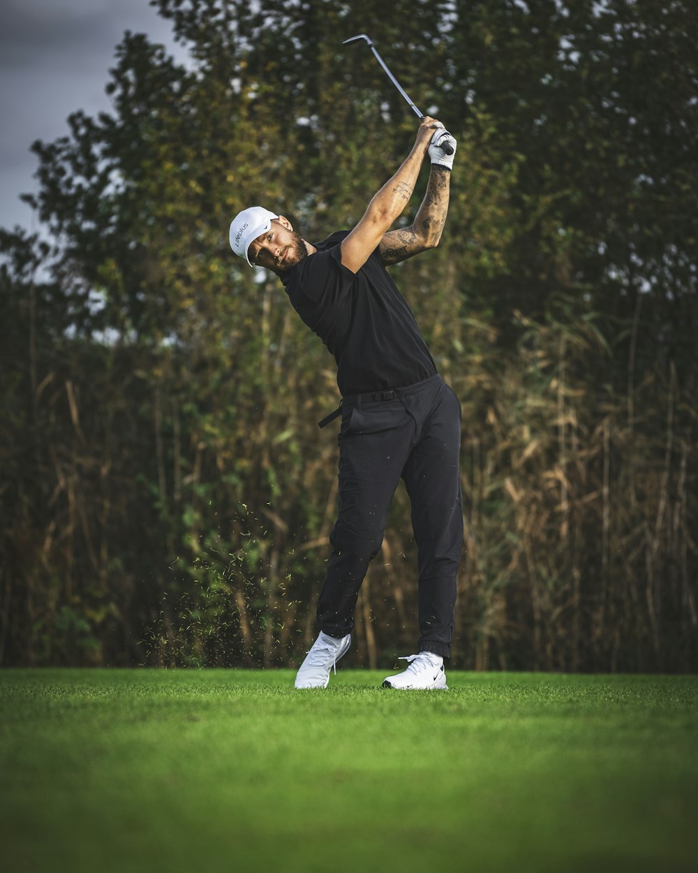 a man swinging a golf club on top of a green field