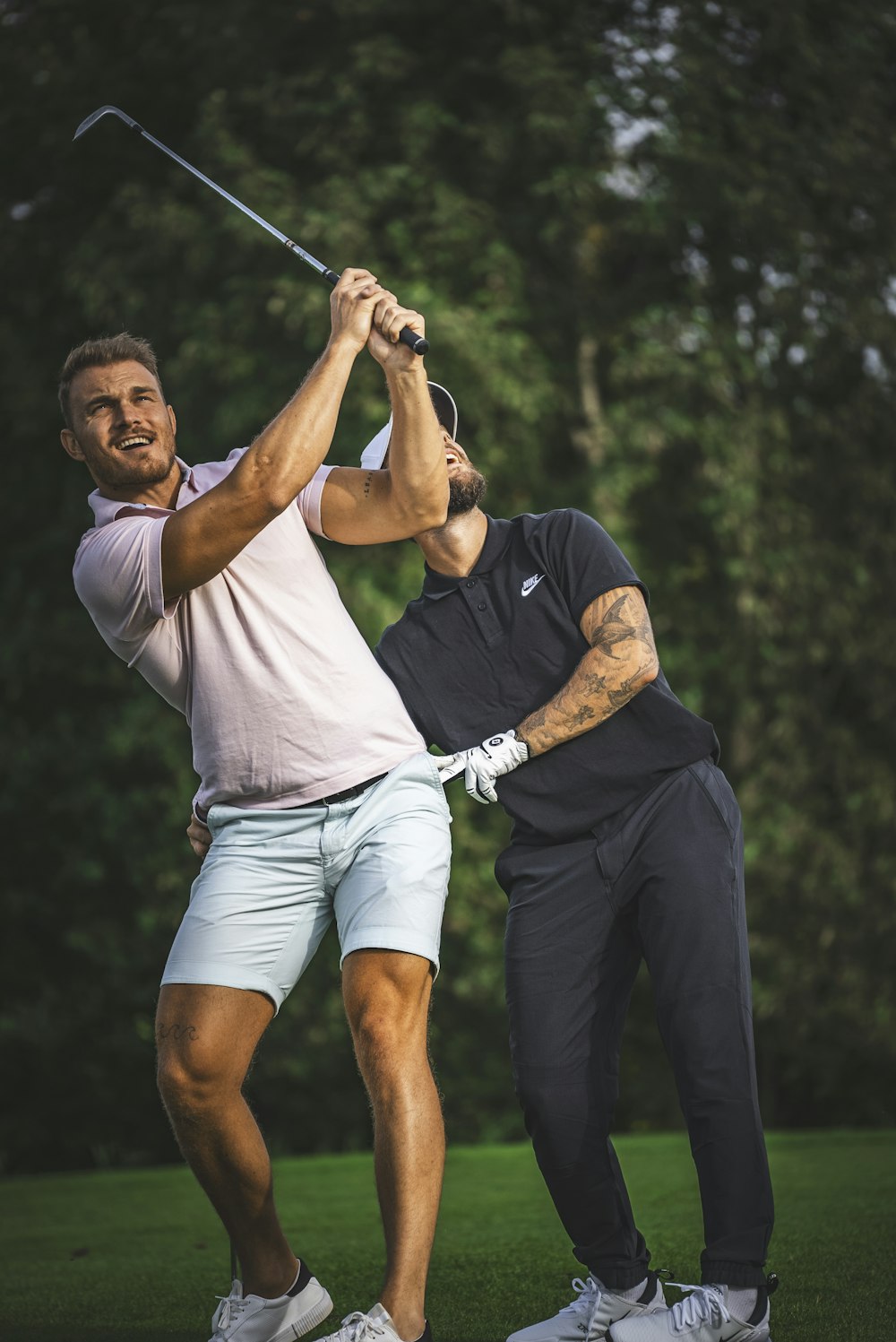 a man holding a golf club while standing next to another man
