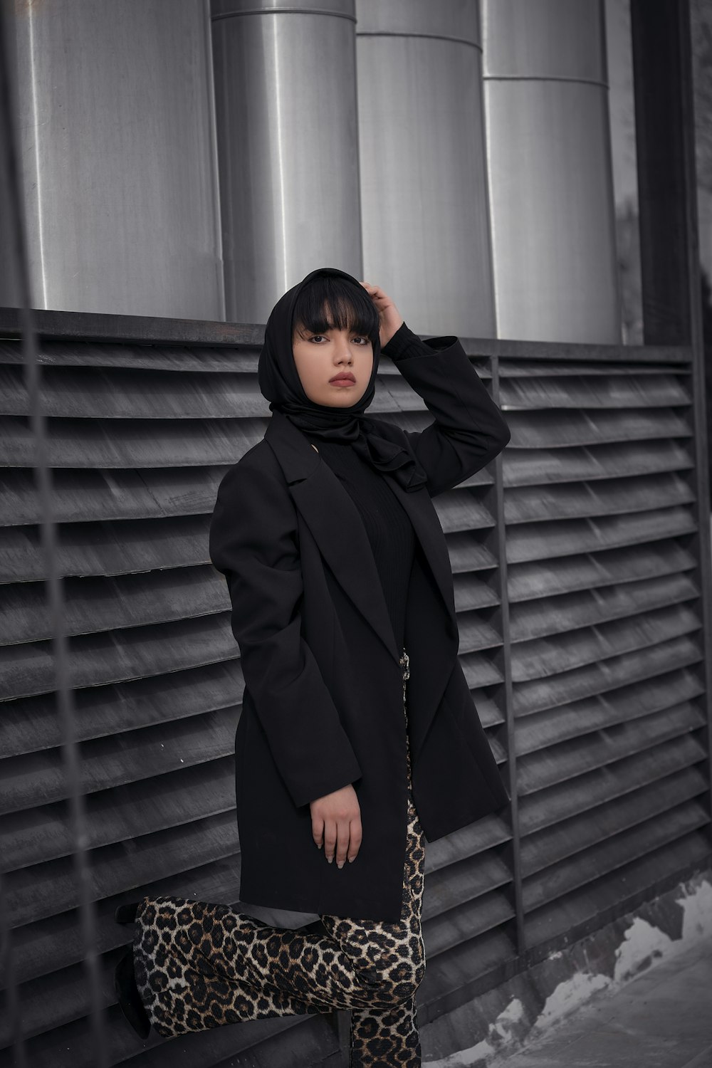 a woman in a black coat and leopard print pants