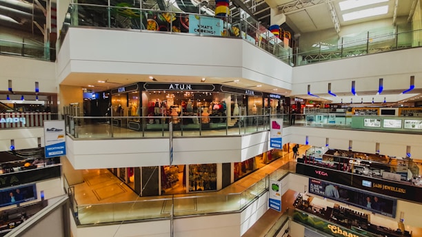 Bright, bustling retail mall interior with various shops and kiosks.