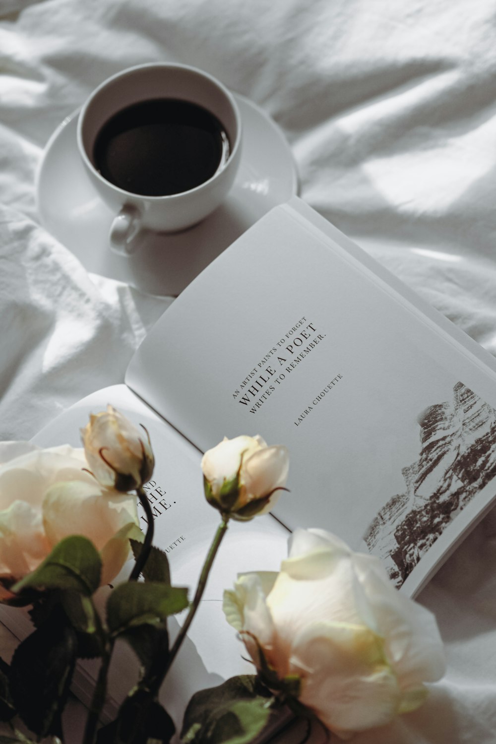 a cup of coffee and a book on a bed