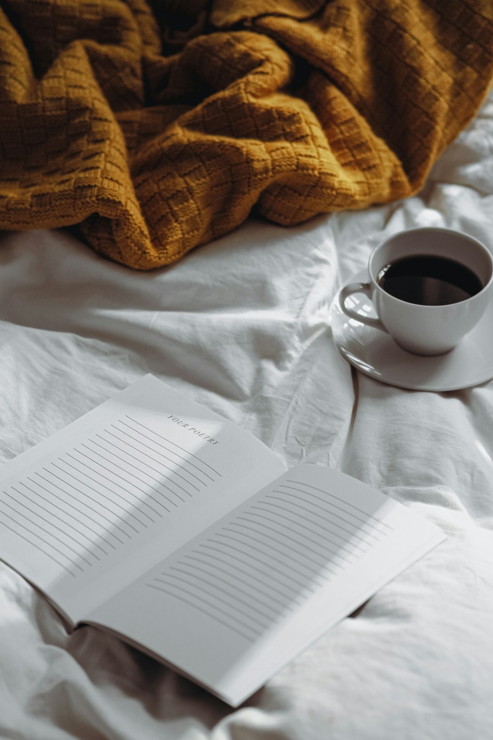 a cup of coffee and a book on a bed