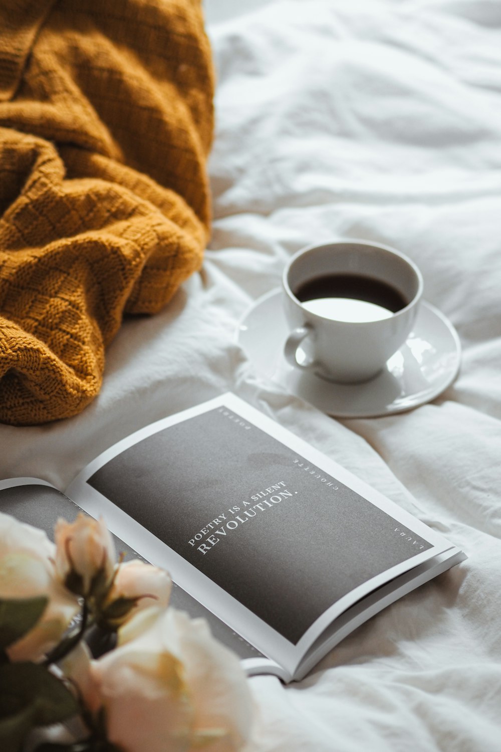 a cup of coffee and a book on a bed