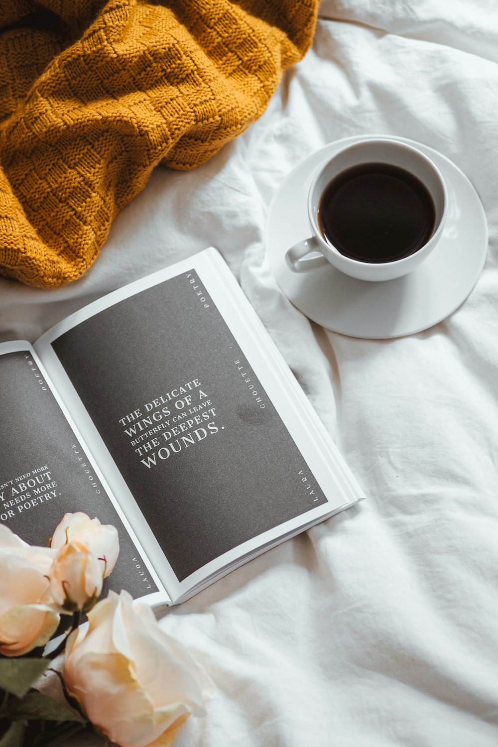 a cup of coffee and a book on a bed