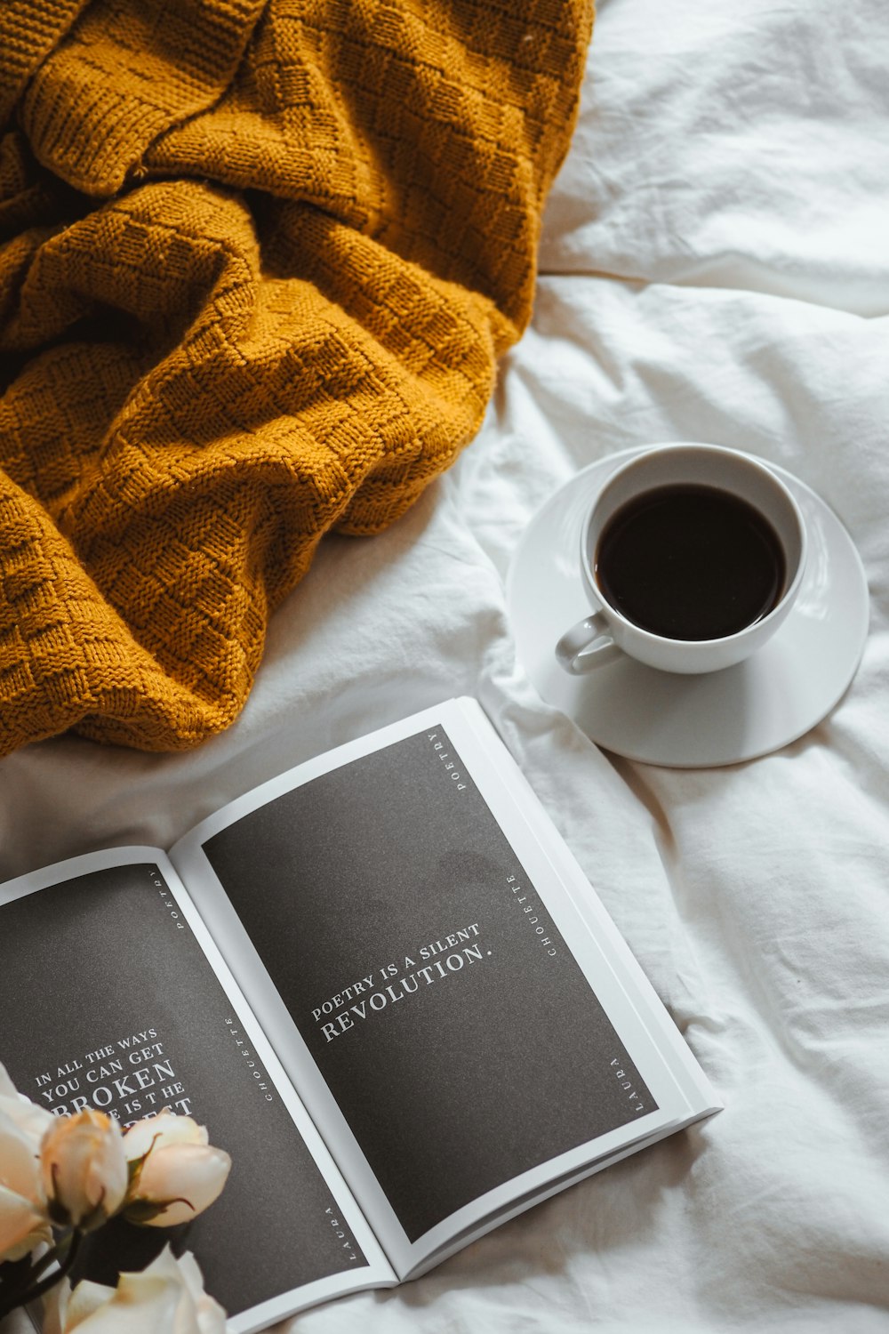 a cup of coffee and a book on a bed