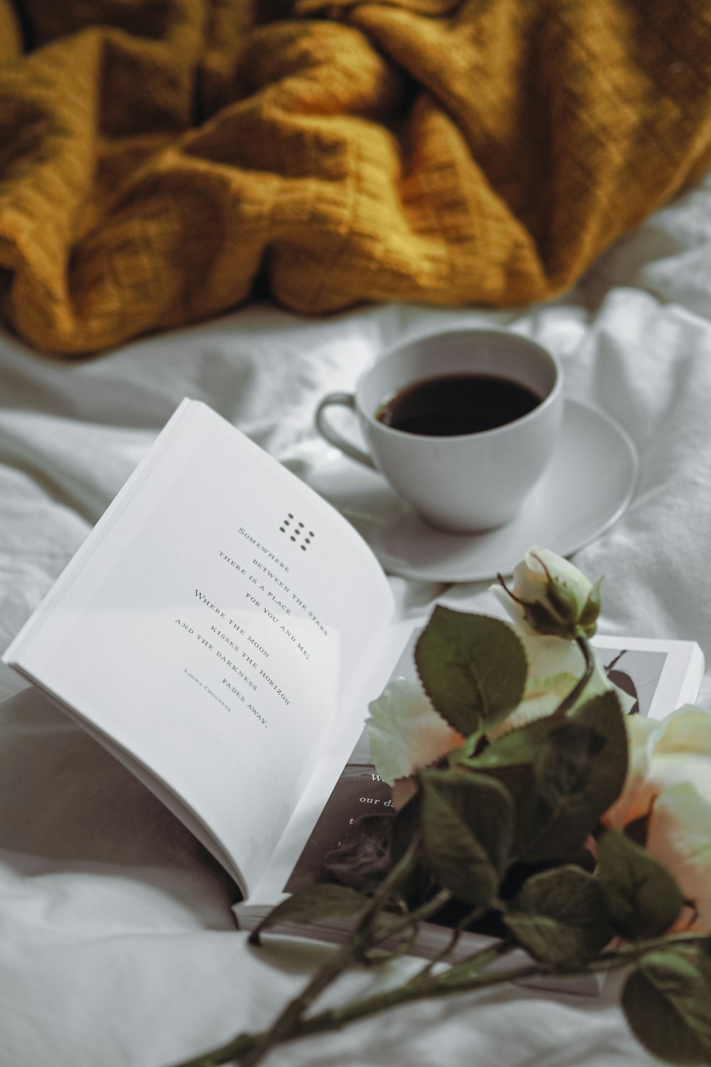 a cup of coffee and a book on a bed