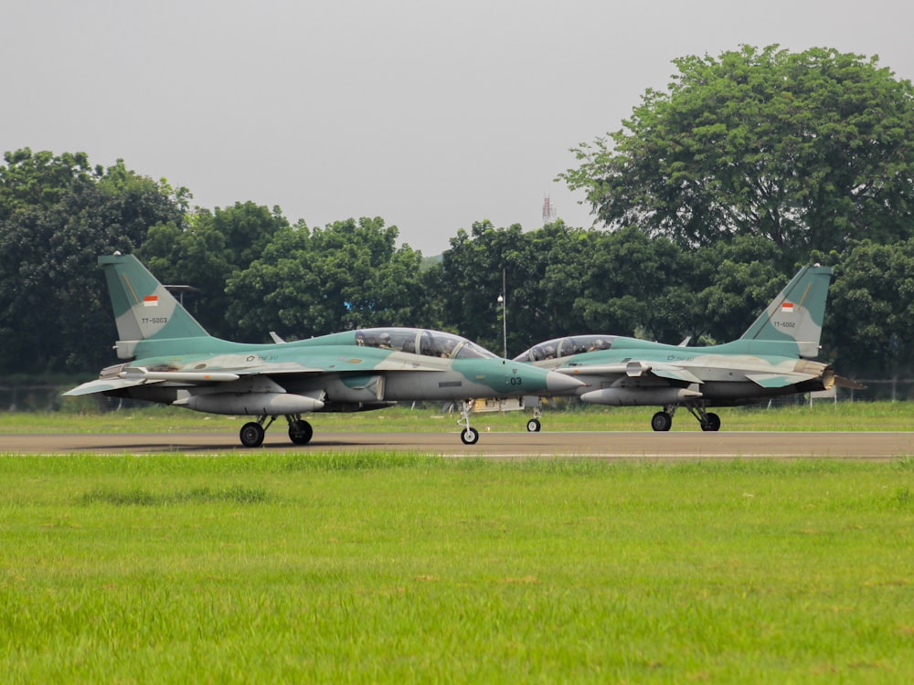 a couple of fighter jets sitting on top of an airport runway