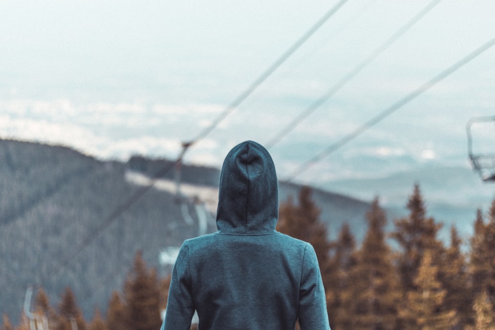 a person in a hoodie standing on a ski slope