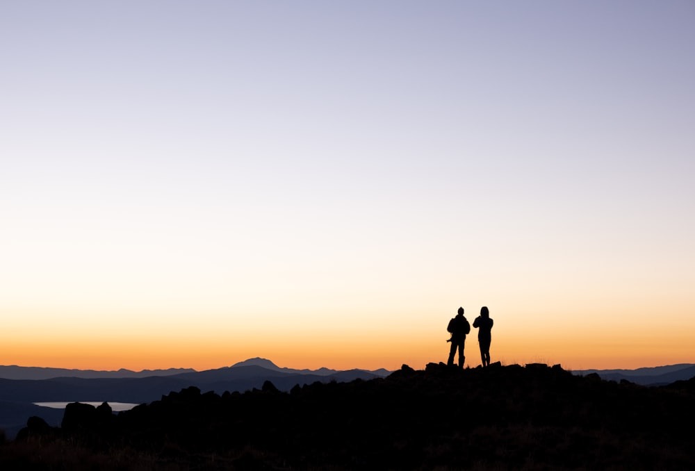 a couple of people standing on top of a mountain