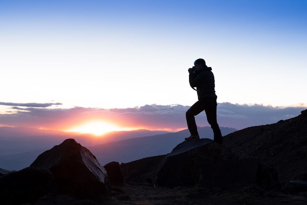 Una persona parada en la cima de una montaña al atardecer