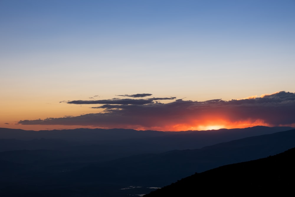 the sun is setting over a mountain range