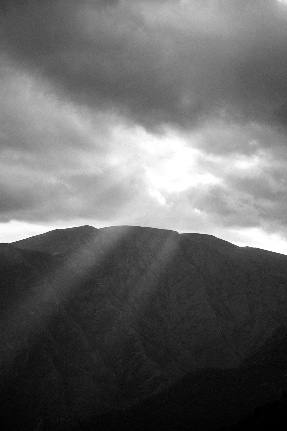 Une photo en noir et blanc du soleil qui brille à travers les nuages