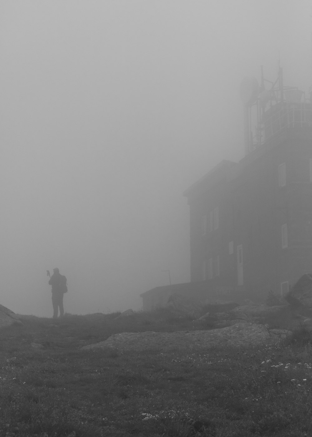 Un hombre parado en la cima de una colina en la niebla