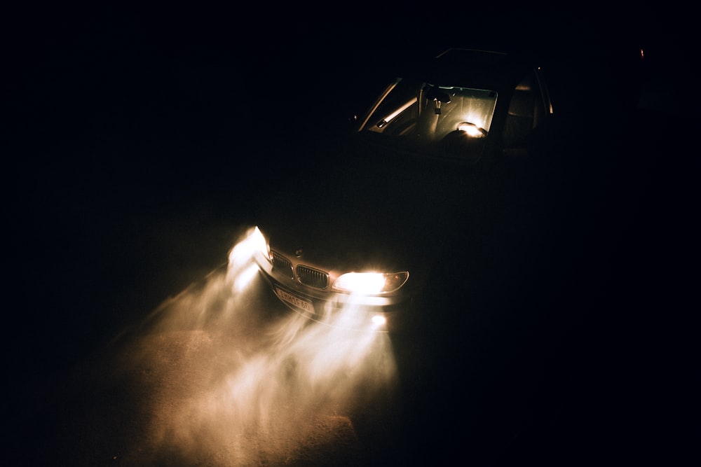 a car driving in the dark with its headlights on