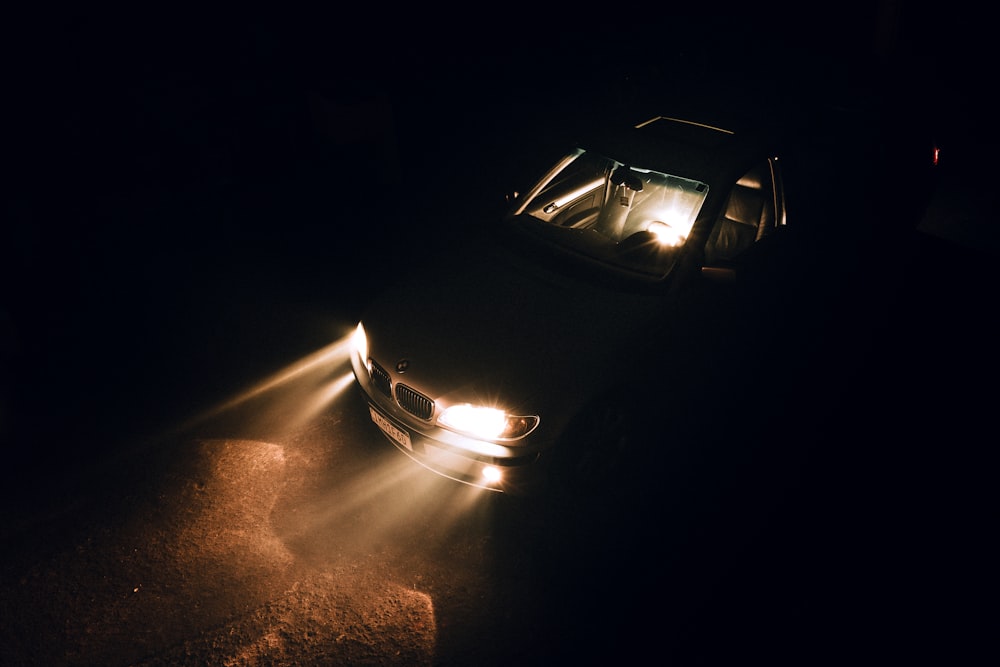 a car with its headlights turned on in the dark
