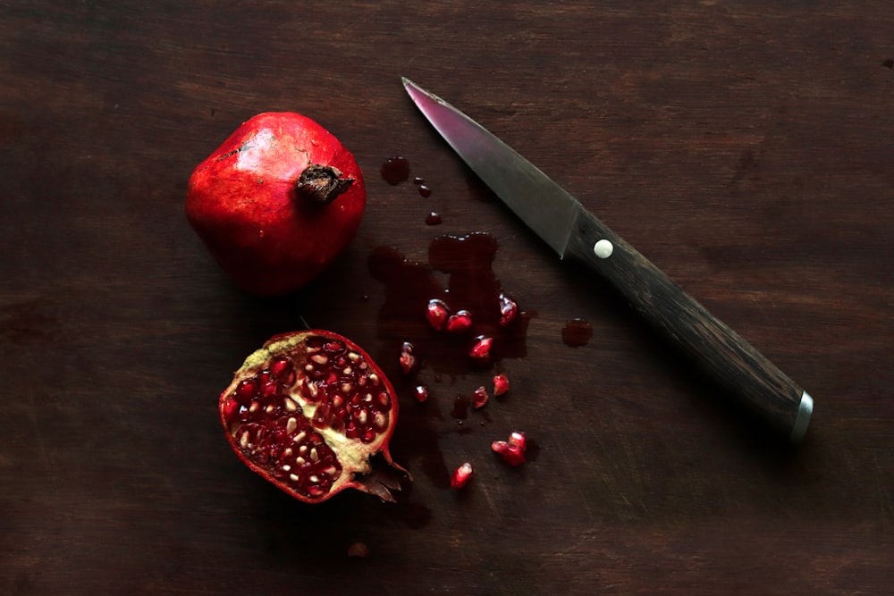 a knife and a pomegranate on a table