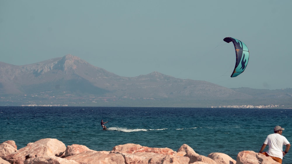 a man flying a kite on top of a rocky beach