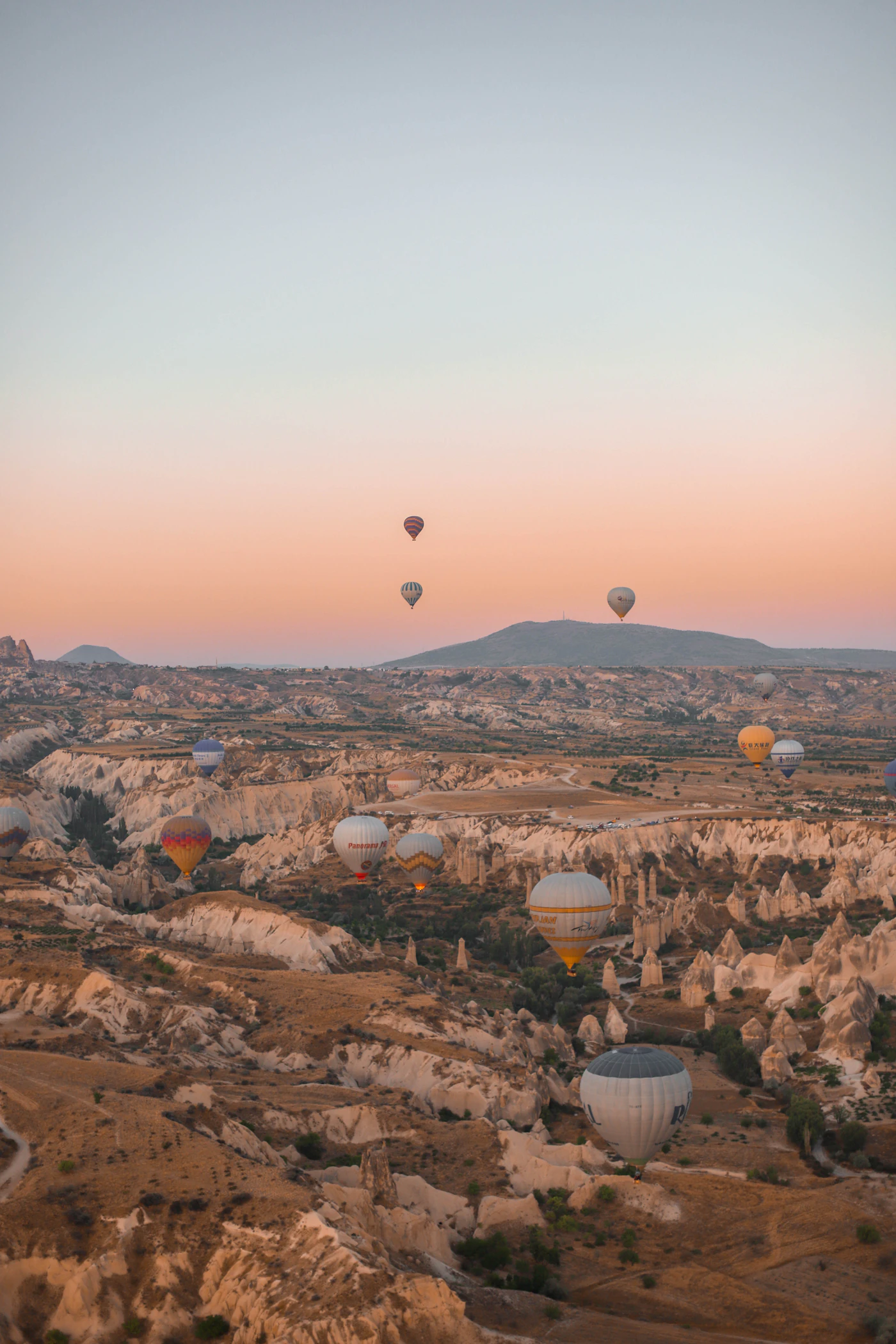 Hot air balloons rising over a valley