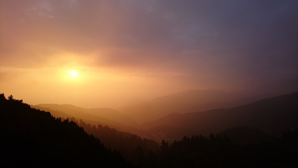 the sun is setting over a mountain range