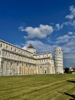 a large building with a tall tower next to a grassy field
