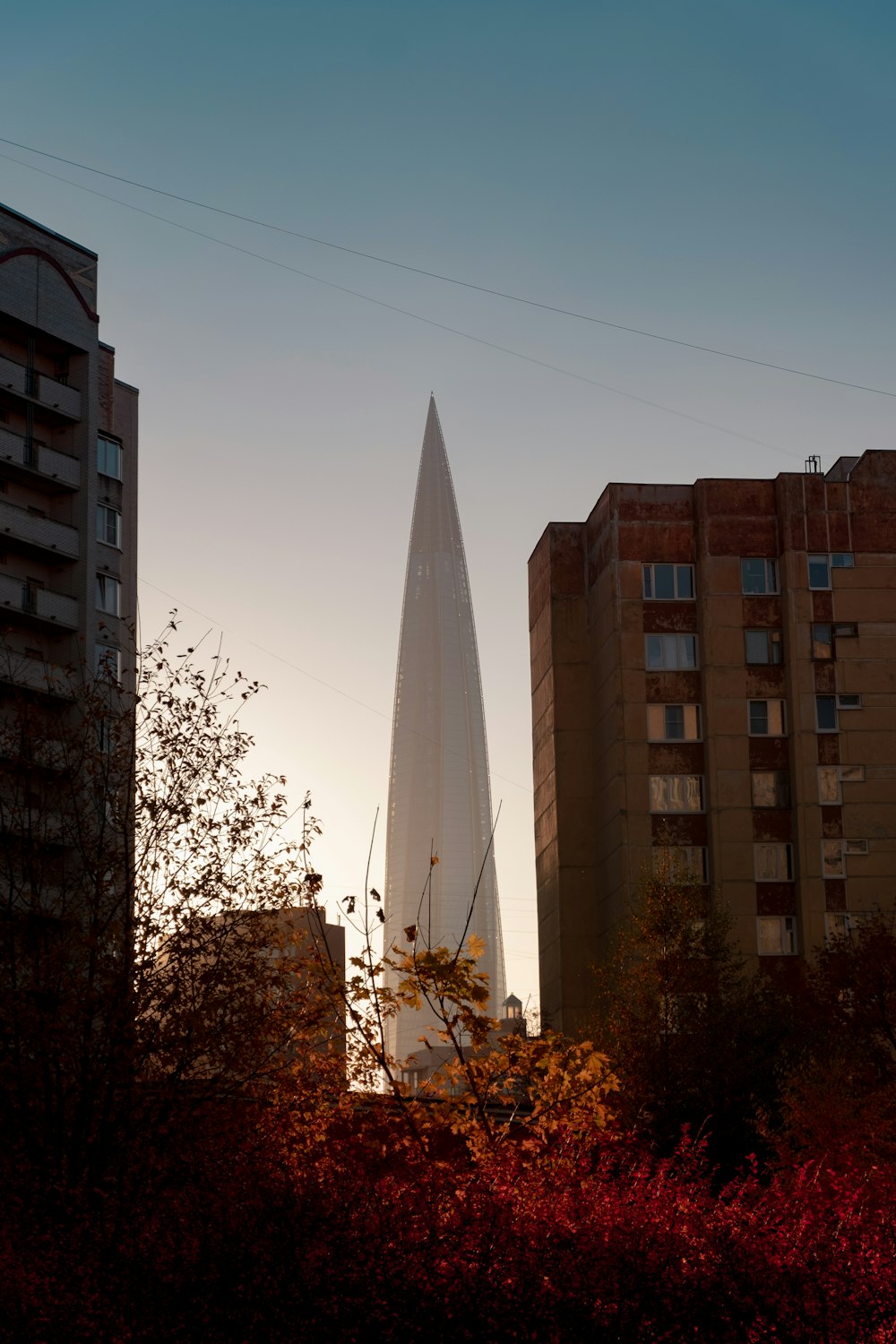 a tall building towering over a city next to tall buildings