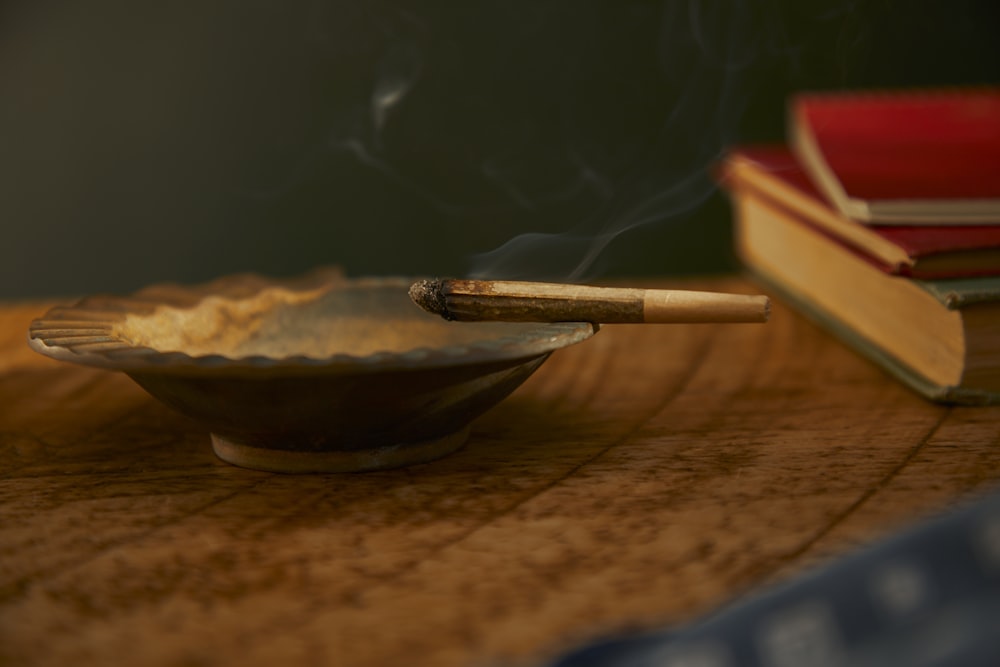 a wooden table with a bowl of smoke and a cigarette