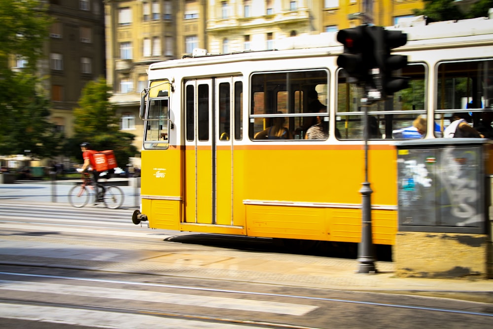 a yellow trolley car is traveling down the street