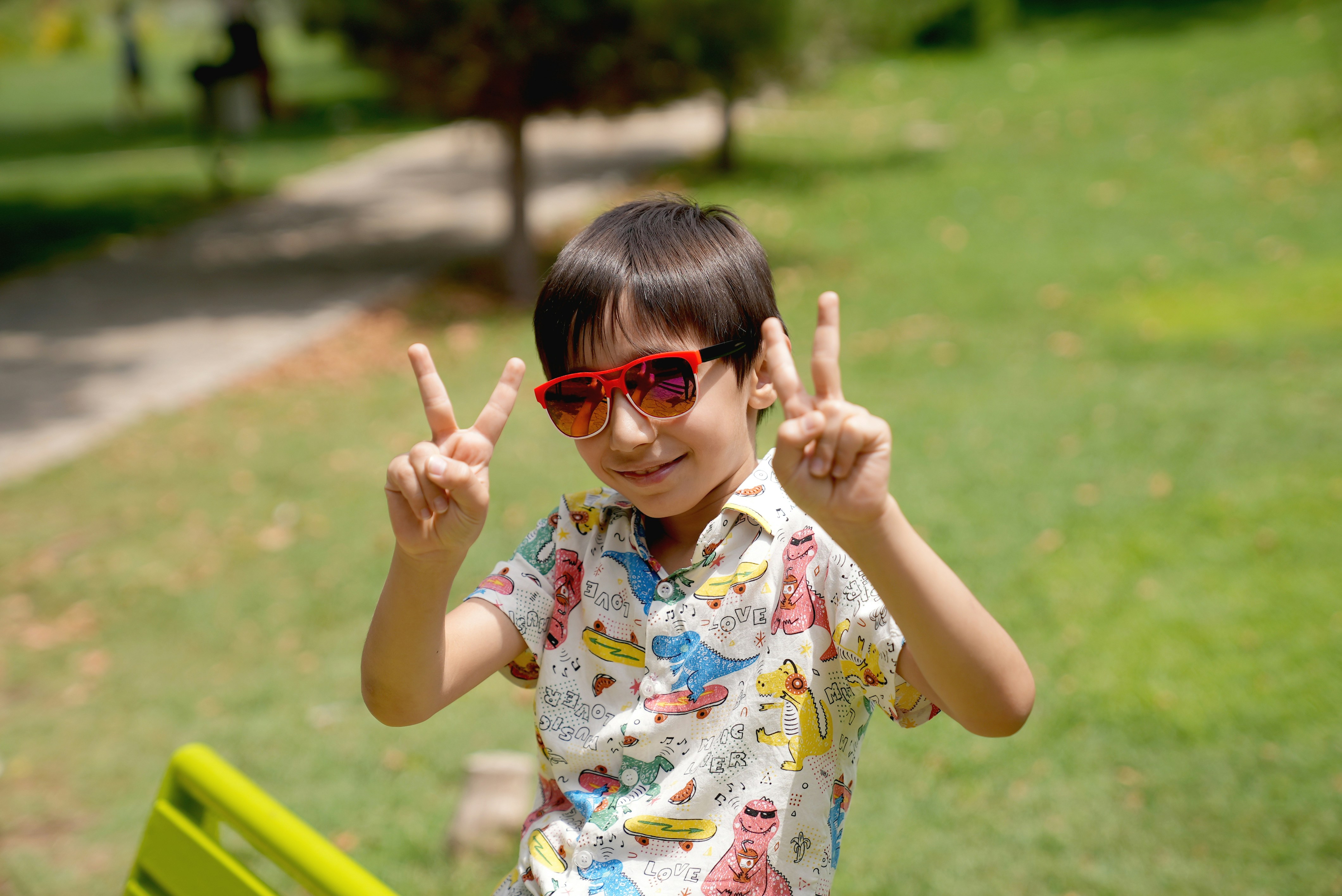 a young boy wearing sunglasses making a peace sign
