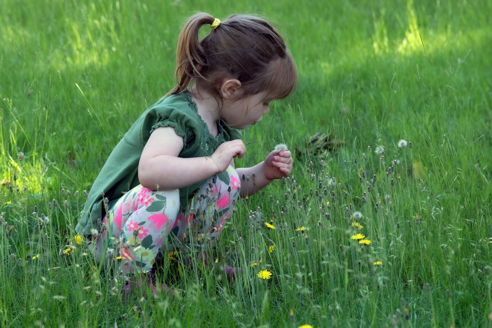 a little girl kneeling down in a field of grass