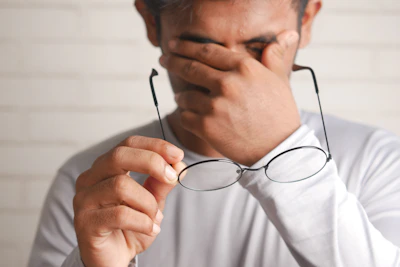 a man holding a pair of glasses up to his face