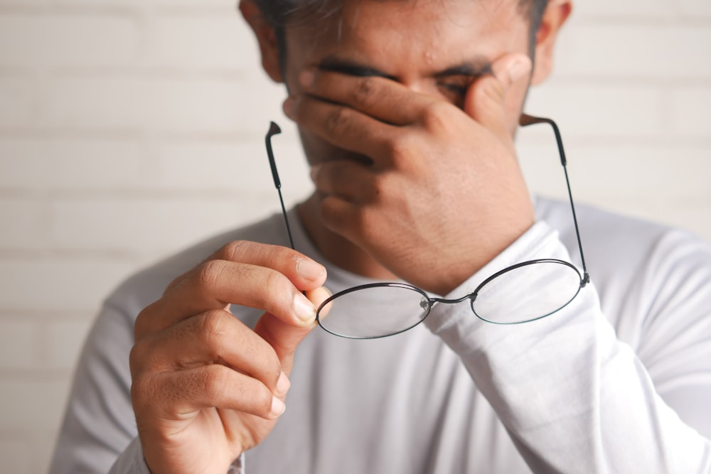 un homme tenant une paire de lunettes contre son visage