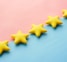 a row of yellow stars sitting on top of a blue and pink surface