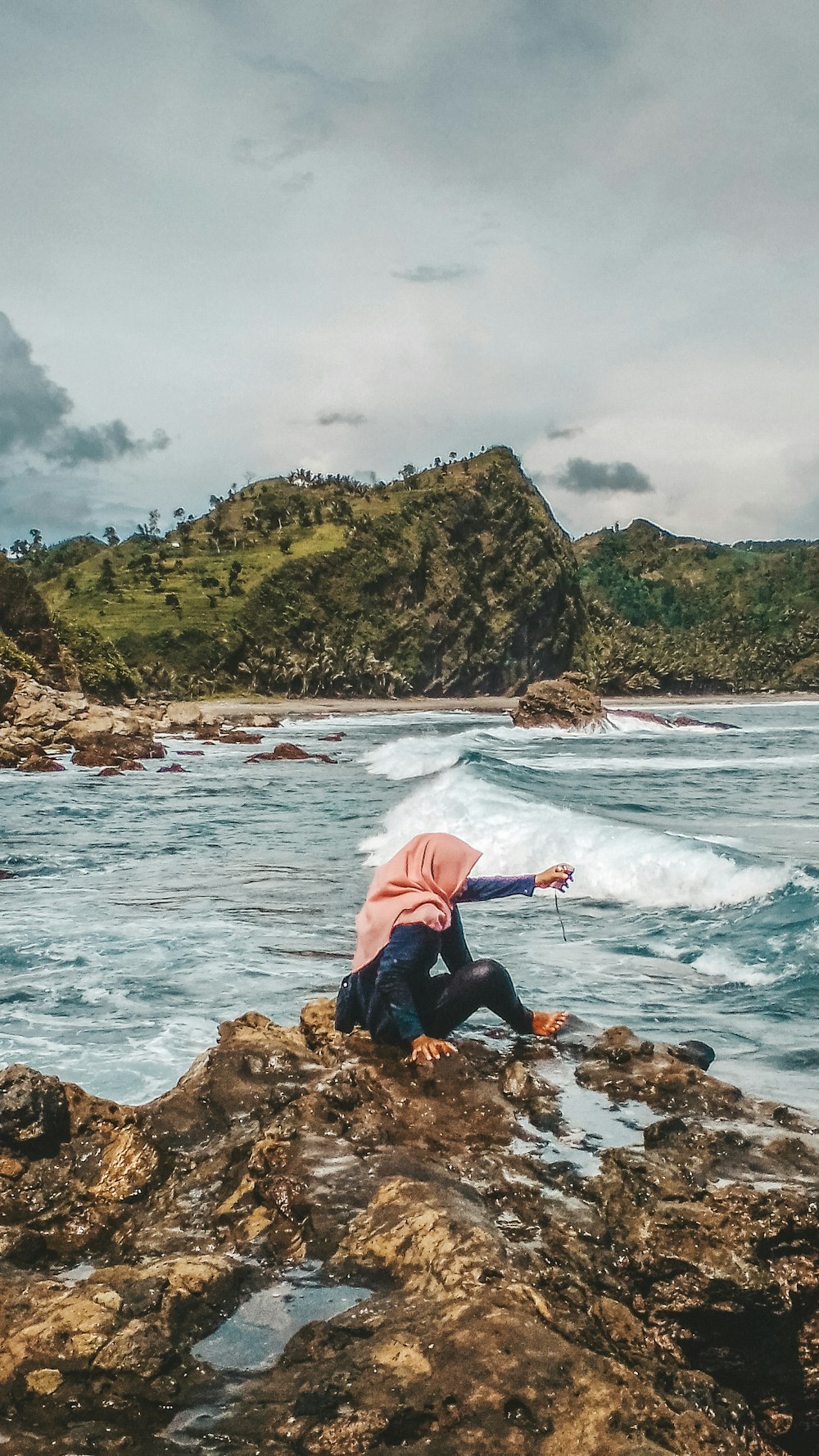 a person sitting on a rock near the ocean