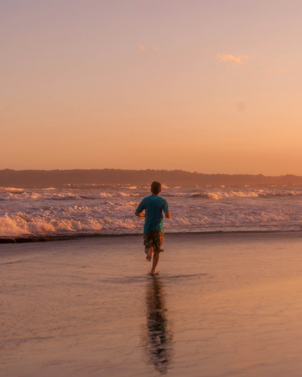 a man is running on the beach at sunset