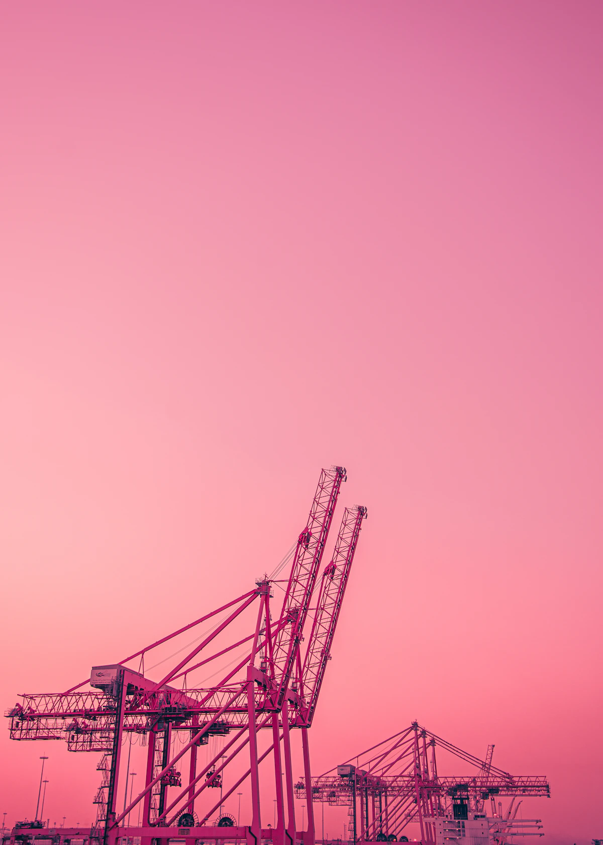 Grues portuaires en silhouette devant un ciel rose au crépuscule
