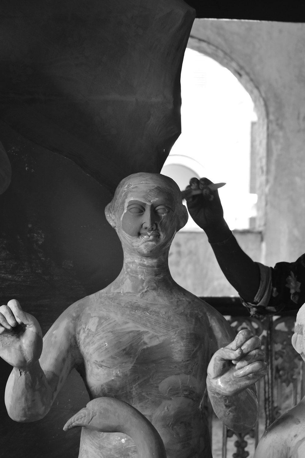 a black and white photo of a man shaving a statue