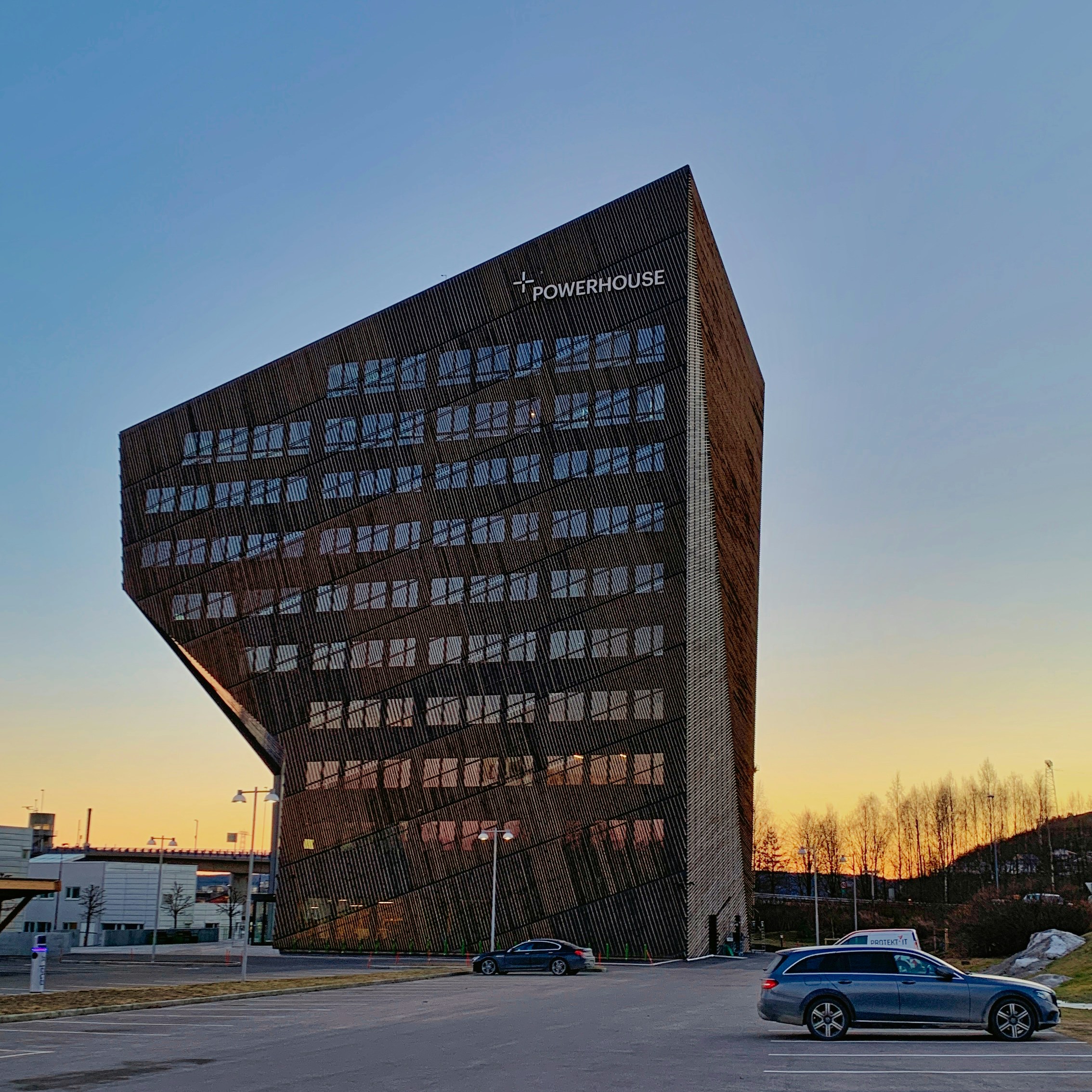 a tall building with many windows next to a parking lot