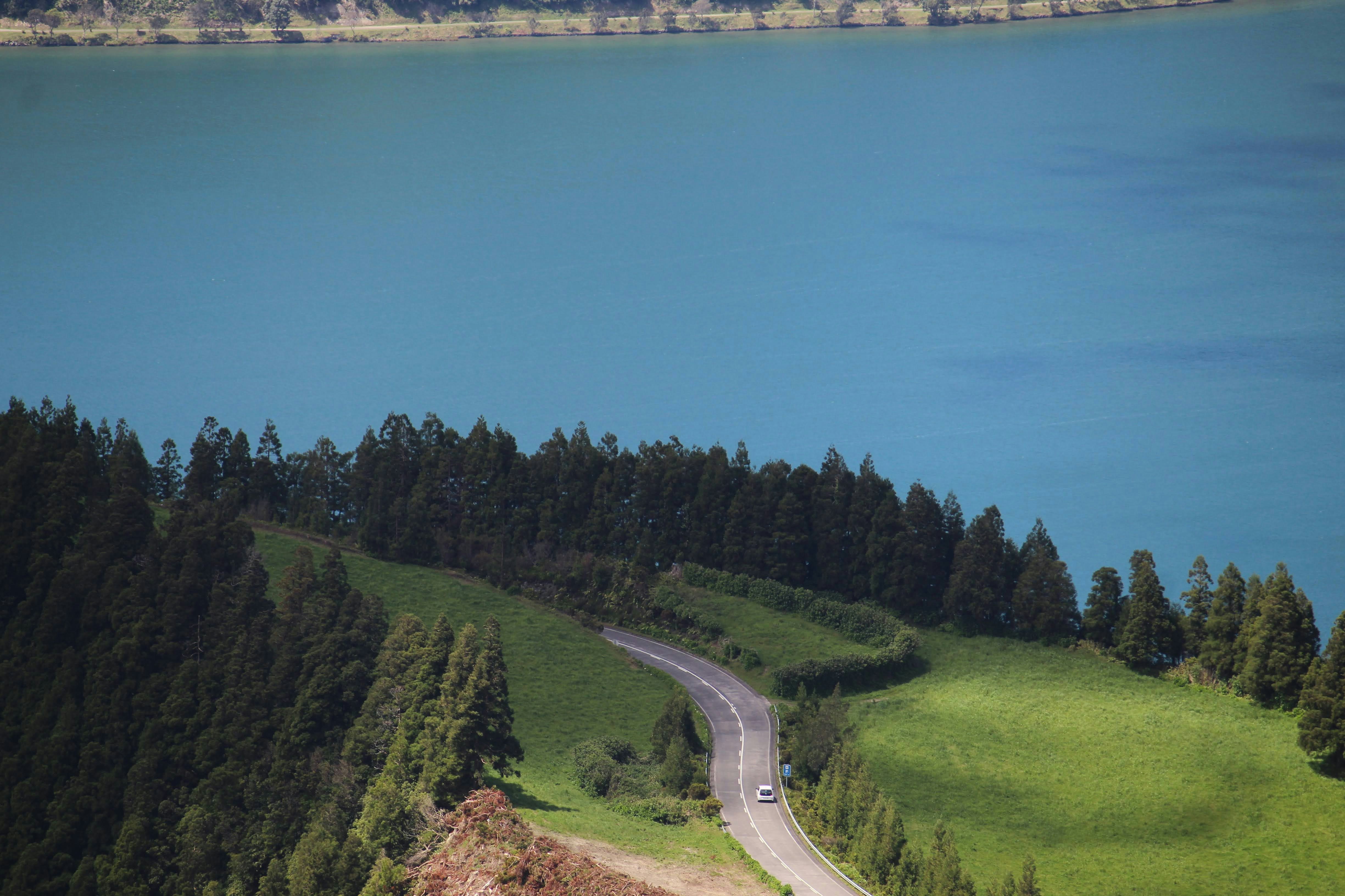 Ein Auto, das eine Straße neben einem großen Gewässer entlang fährt