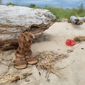 A pair of vibrant red strappy sandals on a sandy beach.