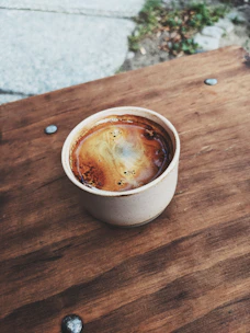 Freshly brewed coffee in a ceramic cup on a rustic wooden table.