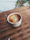 Close-up of freshly brewed coffee being poured into a minimalist ceramic cup on a wooden table.