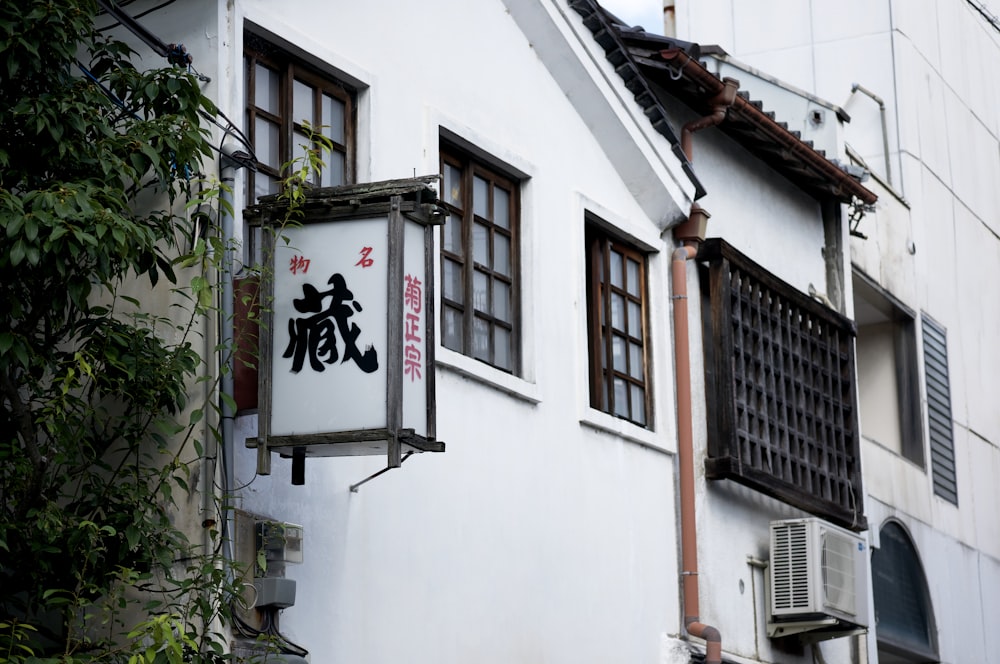 Un bâtiment blanc avec un signe chinois suspendu sur le côté