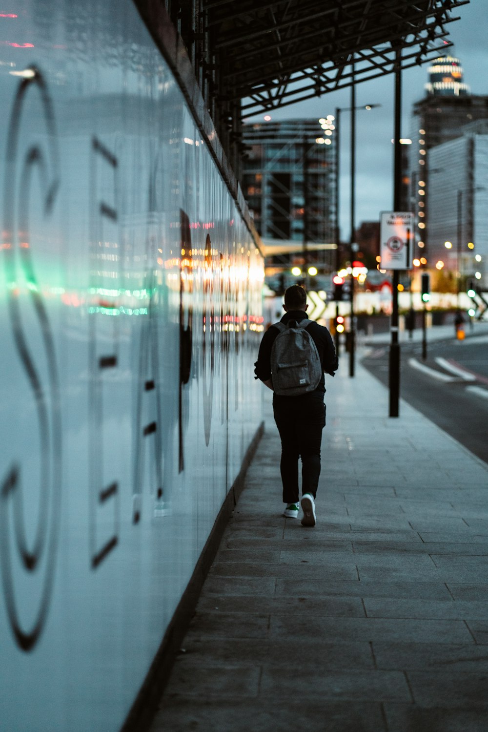 a person walking down a sidewalk next to a building