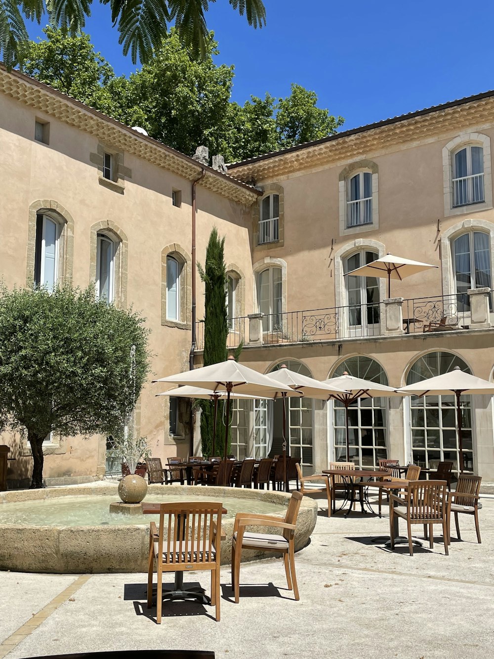 a courtyard with tables, chairs, and umbrellas